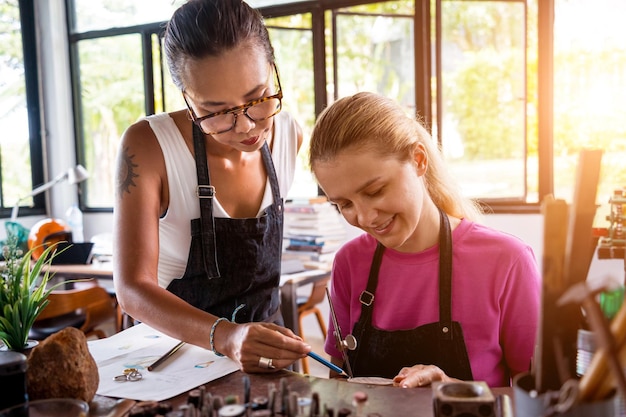 Teacher jeweler and student make jewelry in workshop