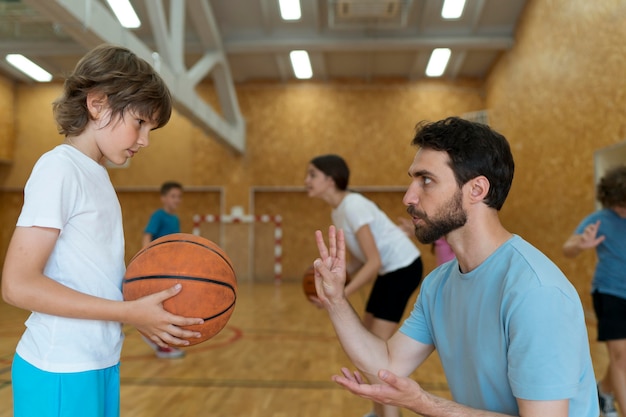 Insegnante e bambino con palla da basket a tiro medio