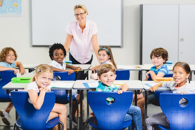 Учитель и дети улыбаются в классе