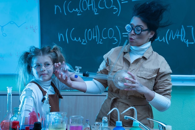 Teacher and little girl during chemistry lesson mixing chemicals