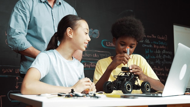 Photo teacher looking at laptop screen while explain car model system edification