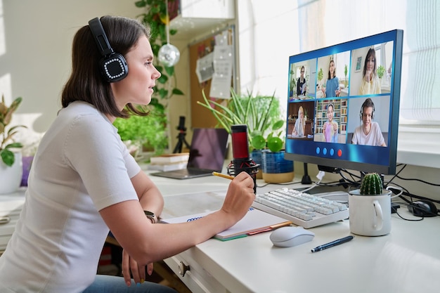 Teacher looking at pc screen online lesson with group of teenage students