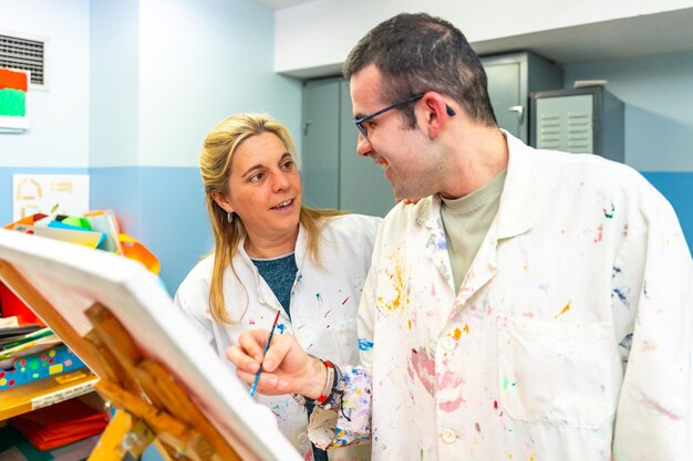 Teacher of a painting class talking to a disabled student