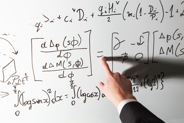 Фото Учитель указывает пальцем на математический символ равенства на доске математика и наука с экономической концепцией реальные уравнения символы, написанные вручную профессионалом