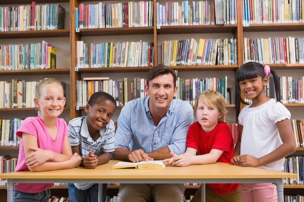 Insegnante ed allievi che sorridono alla macchina fotografica alla biblioteca