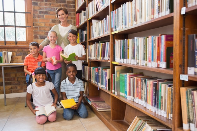 Photo teacher and pupils smiling at camera at library