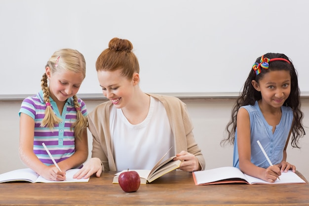 Teacher and pupils working at desk together 