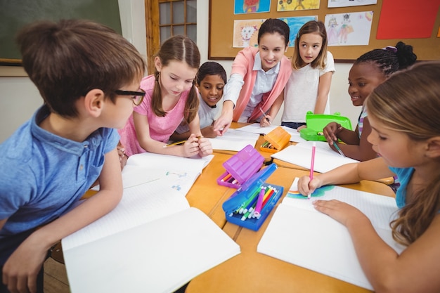 Teacher and pupils working at desk together