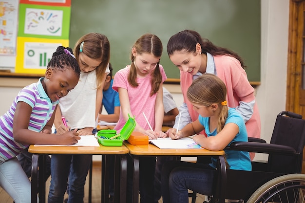 Foto insegnante ed allievi che lavorano insieme allo scrittorio