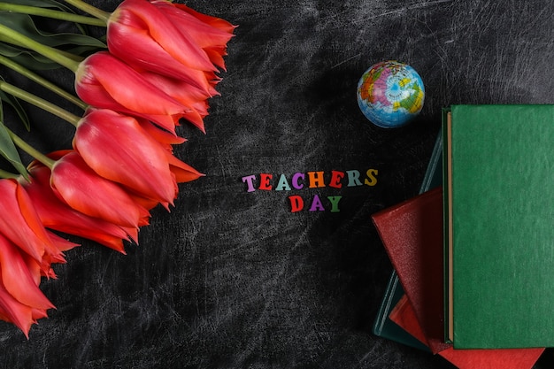 Фото День учителя или день знаний. красные тюльпаны, стопка книг, глобус на доске мелом. вид сверху. обратно в школу