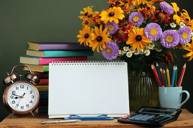 Teacher's day, September 1. To go back to school. Bouquet of autumn flowers, alarm clock and an outdoor album with a spiral at the base