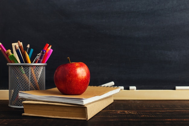 Teacher's desk with writing materials, a book and an apple