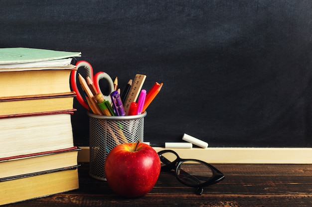 Teacher's desk with writing materials, a book and an apple