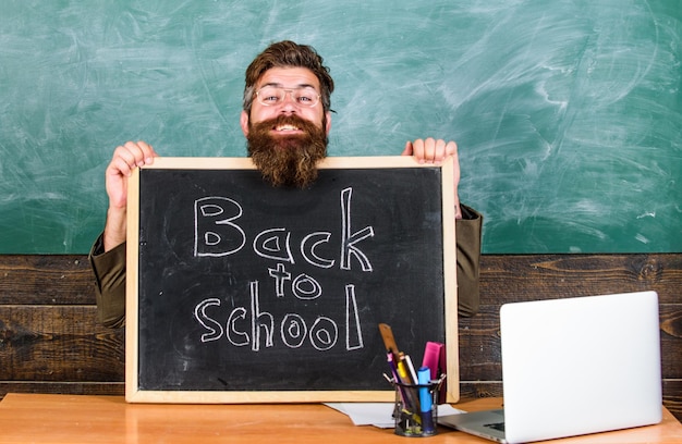 Teacher or school principal welcomes with blackboard inscription back to school Welcome back Beginning of new school year in september Teacher welcomes new pupils to enter educational institution