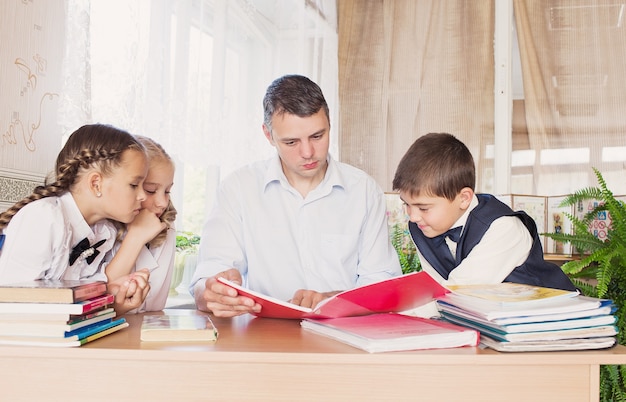 Un insegnante a scuola insegna ai bambini a leggere con attenzione un libro