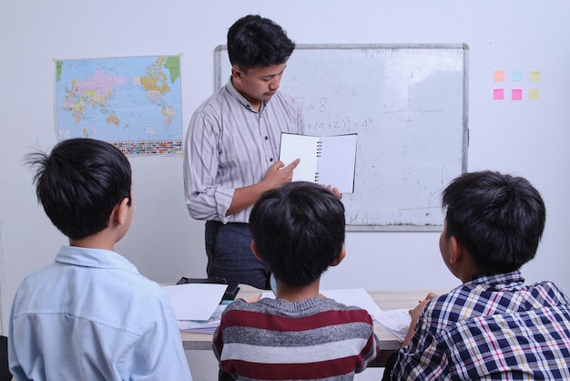 교실에서 학생들에게 책에 대한 지침을 보여주는 교사