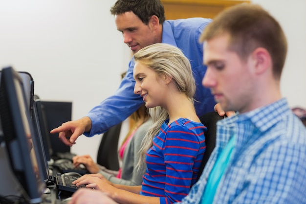 Teacher showing something on screen to student in computer room