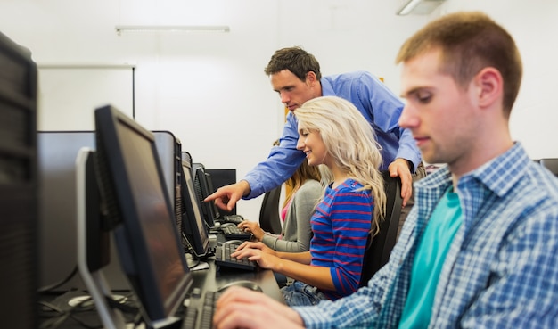 Teacher showing something on screen to student in computer room