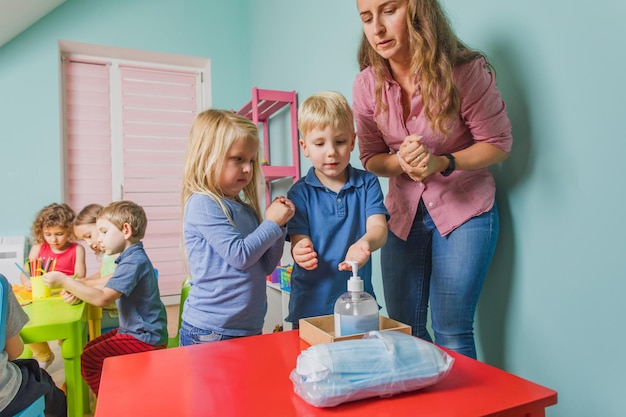 Teacher shows little kids how to sanitize hands