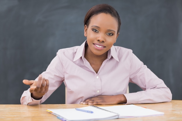 Teacher sitting at desk next to a notebook