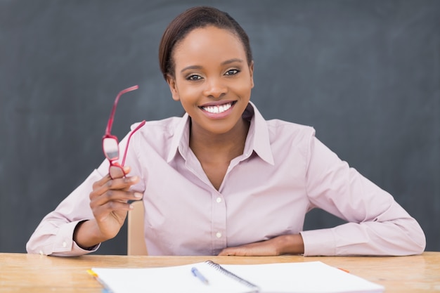 Teacher sitting at desk while holding glasses