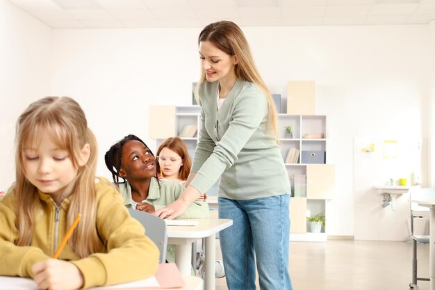 Foto teacher standing near african american boy while helping her with test in the classroom