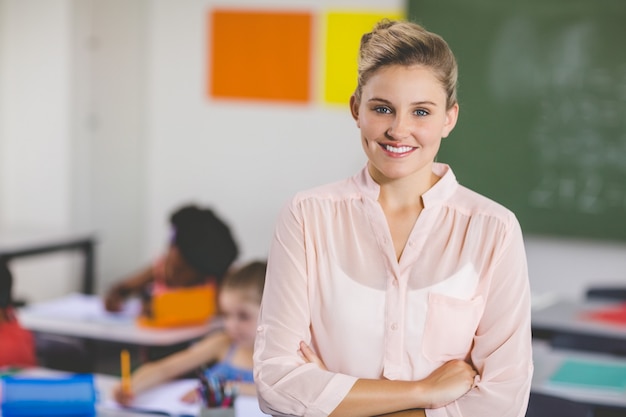 Photo teacher standing with arms crossed in classroom