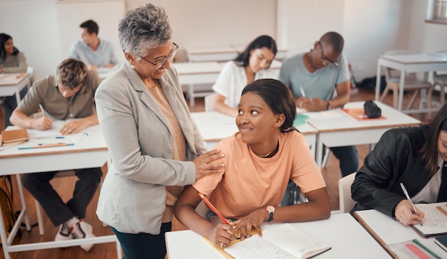 Photo teacher student and classroom for test knowledge and learning for higher education young female black woman or educator helping pupil in exams talking or students writing notes in books or focus