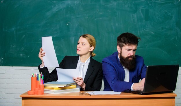 学校に戻って試験中の教師と学生正式な教育ビジネスマンと秘書の紙の仕事オフィスライフ真面目なビジネスカップルはラップトップとドキュメントを使用しています結果を確認する私の仕事が大好きです