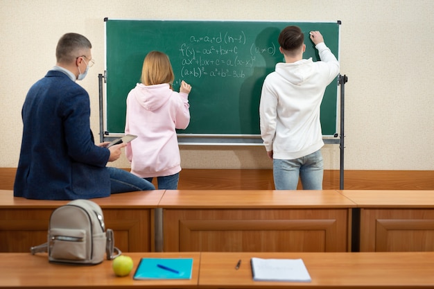 Teacher and students wearing protective masks near the blackboard during quarantine