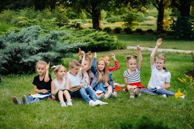 教師が屋外の公園で子供たちのクラスを教えています。学校に戻り、パンデミックの最中に学びます。