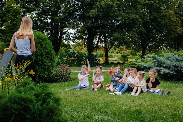 A teacher teaches a class of children in an outdoor Park. Back to school, learning during the pandemic.