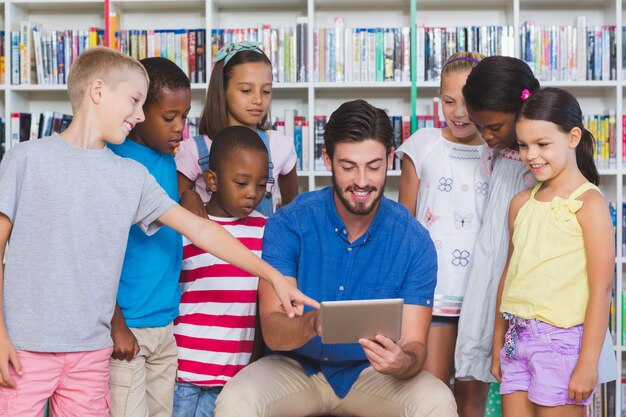 Учитель учит детей на цифровой планшет в библиотеке