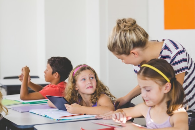 Photo teacher teaching kids on digital tablet