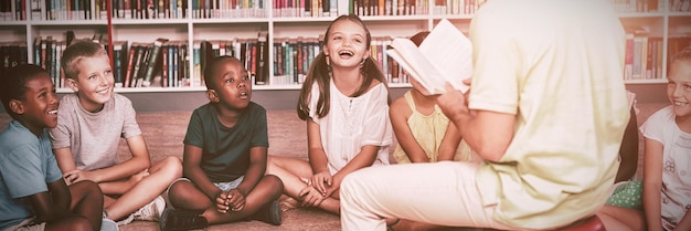 Photo teacher teaching kids in library