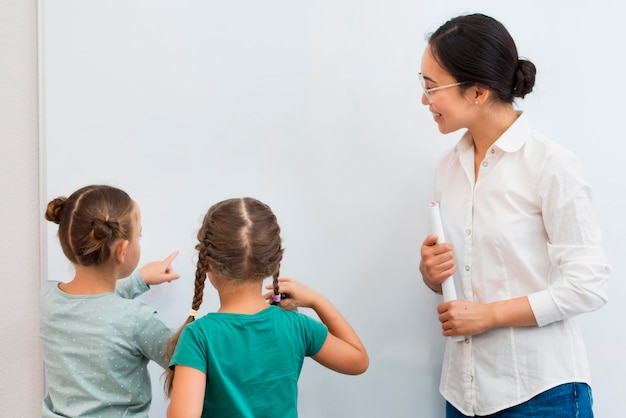 Photo teacher telling her students what to write on a white board