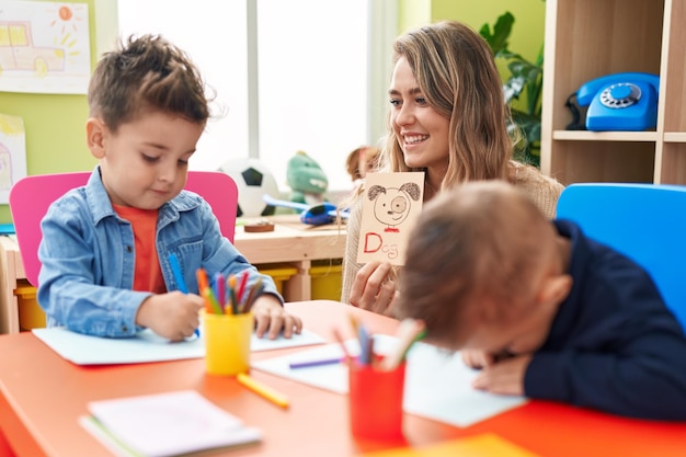 Teacher with boys sitting on table having language lesson at kindergarten