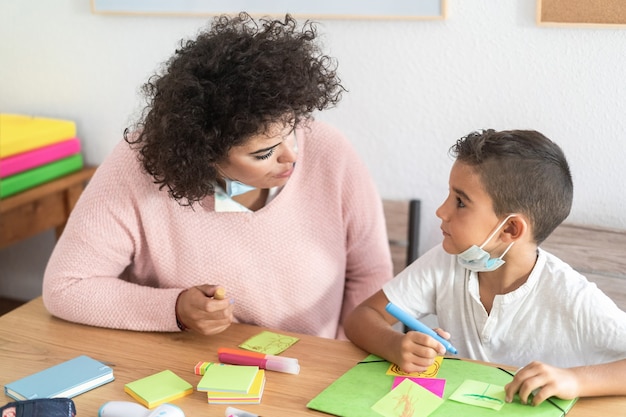 Teacher working with child boy at preschool during coronavirus outbreak - Soft focus on woman eye