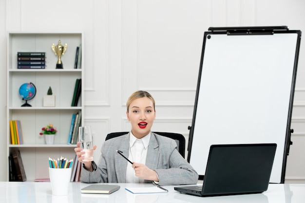 Teacher young cute instructor in suit in classrom with laptop and whiteboard holding glass water