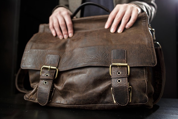 Photo teachers female hands hold on to an antique brown leather briefcase