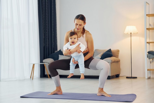 Teaching fitness Mother with her little daughter is at home together