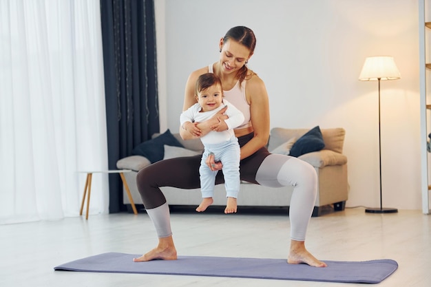 Teaching fitness Mother with her little daughter is at home together