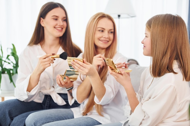 Teaching how to do make up Young mother with her two daughters at home at daytime