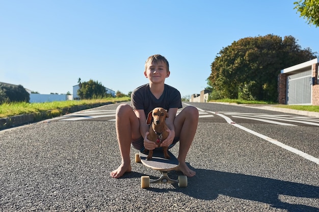 Teaching my dog has to skate Full length portrait of a young boy and his dog sitting on a longboard