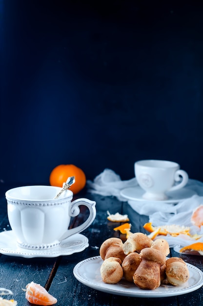 Tazza da tè con angelo tè e biscotti, tangerineon un tavolo nero