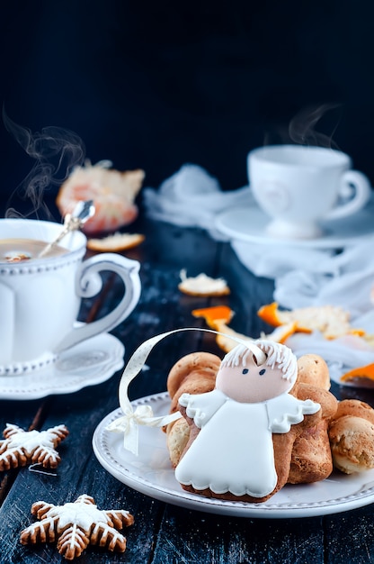 Teacup with tea and biscuits angel, tangerineon a black table 