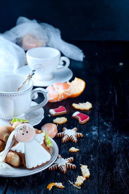 Tazza da tè con angelo tè e biscotti, tangerineon un tavolo nero