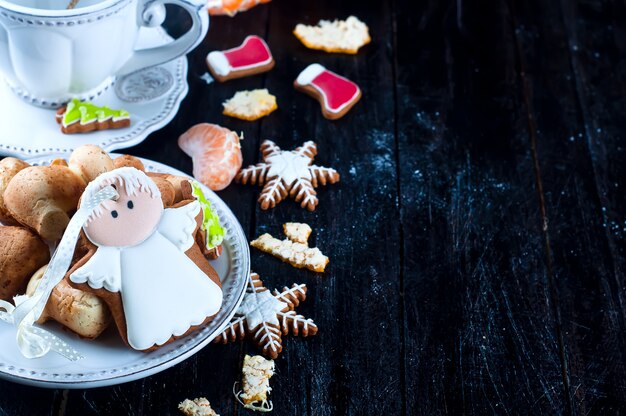 Teacup with tea and biscuits angel, tangerineon a black table 