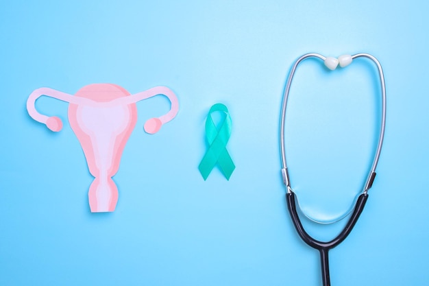 Photo teal awareness ribbon with stethoscope and uterus shape for ovarian cancer month