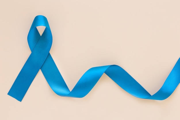 Teal color ribbon curl on white or beige isolated background, copy space.